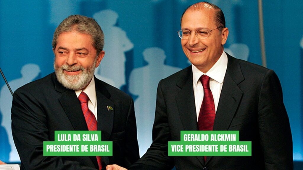 "Fotografía oficial de Luiz Inácio Lula da Silva y Geraldo Alckmin sonriendo y dándose la mano. Ambos visten trajes oscuros y corbatas rojas sobre camisas blancas. Lula está a la izquierda y Alckmin a la derecha. Debajo de cada uno hay un bloque de texto verde con su cargo. La imagen transmite una alianza política formal y de unidad."